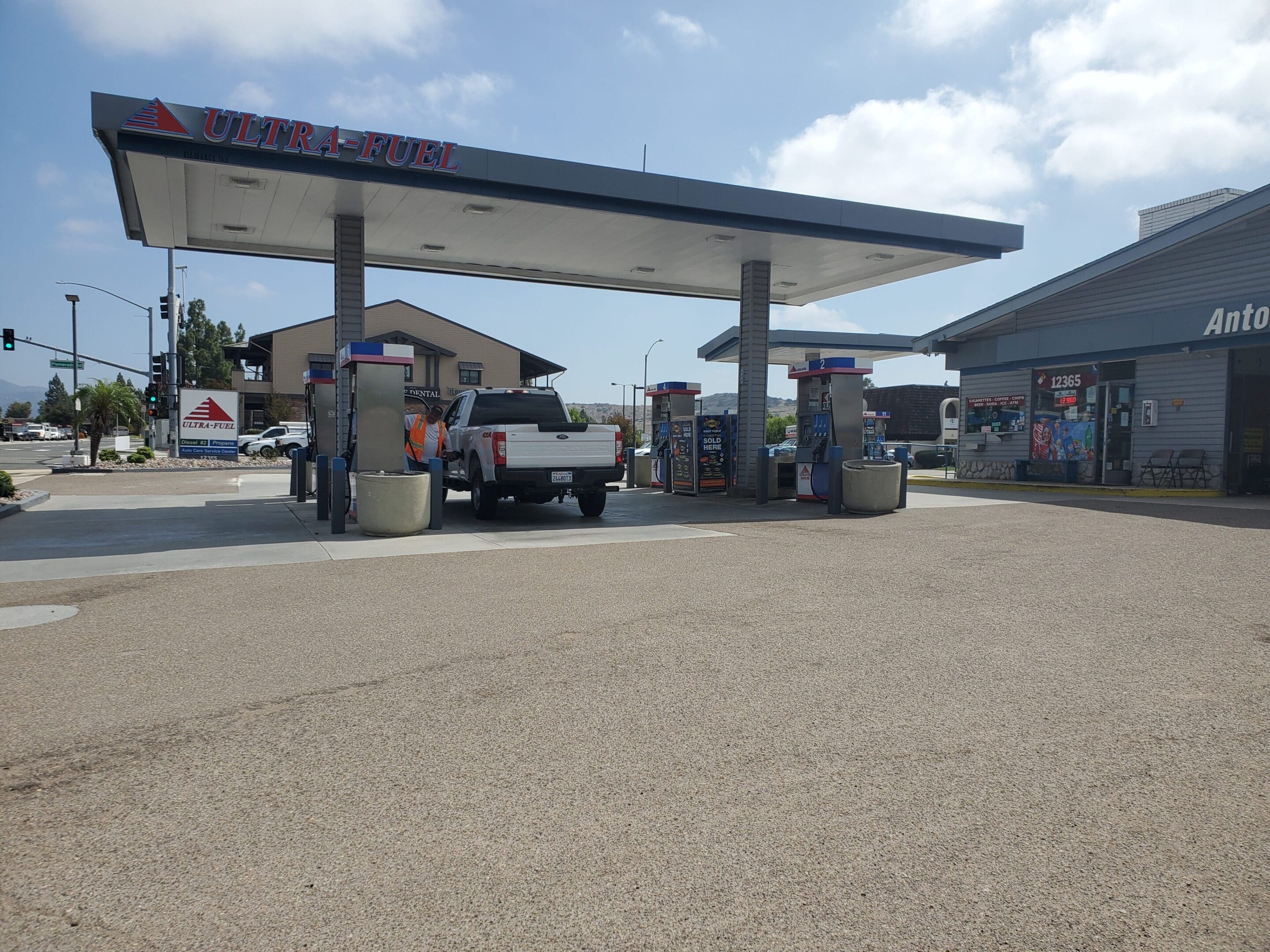 A truck parked at the gas station with other vehicles.